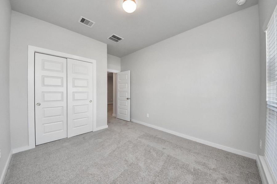 Inviting guest suite. The room features elegant 5-panel doors with sleek, contemporary hardware. Sink your feet into the plush, fluffy carpet that invites comfort and warmth. Large windows flood the space with an abundance of natural light, framed by privacy blinds that offer the perfect balance between openness and seclusion. Sample photo of completed home with similar floor plan. Actual colors and selections may vary.