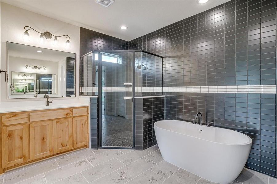 Bathroom with tile flooring, vanity, tile walls, and independent shower and bath