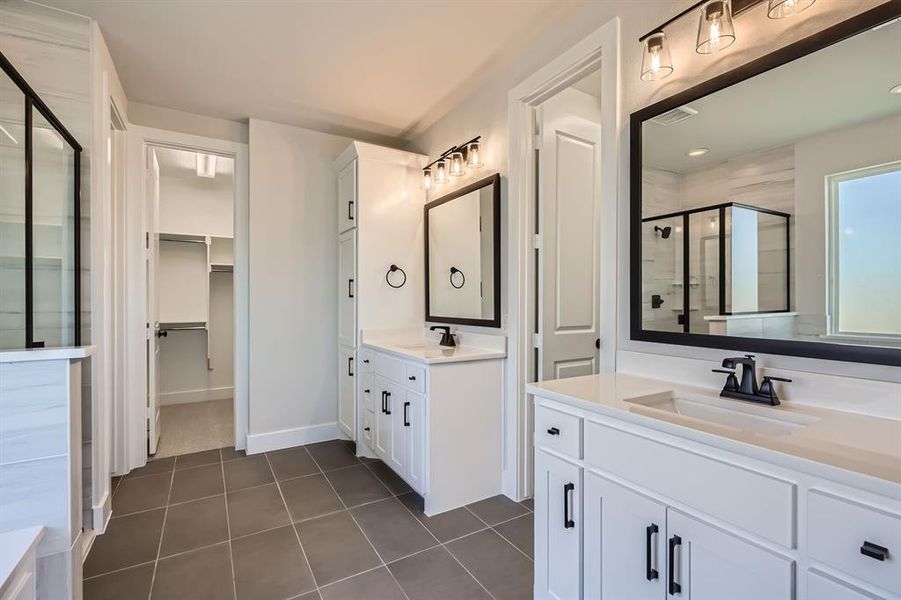 Full bathroom with a stall shower, tile patterned floors, two vanities, and a spacious closet Full bathroom with a stall shower, tile patterned floors, two vanities, and a spacious closet