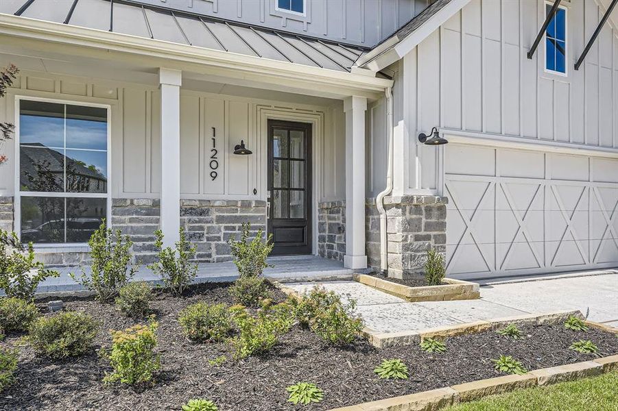 Doorway to property featuring a standing seam roof, board and batten siding, and stone siding Doorway to property featuring a standing seam roof, board and batten siding, and stone siding