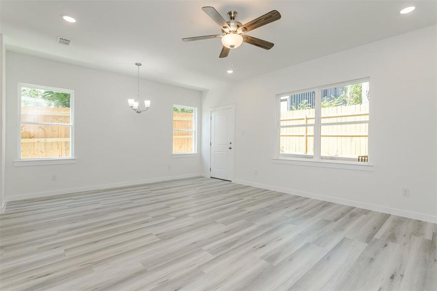 Unfurnished room featuring light hardwood / wood-style floors and ceiling fan with notable chandelier