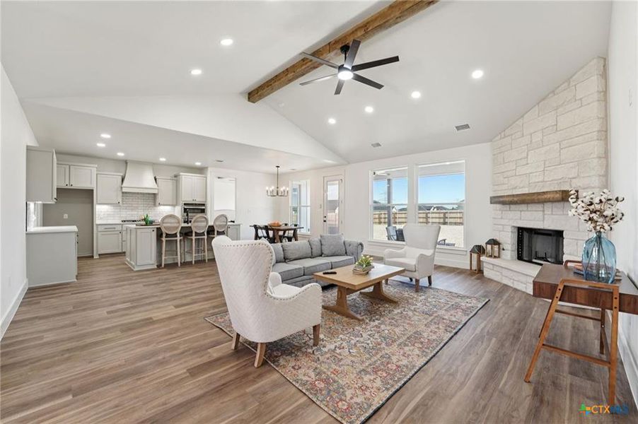 An open-concept living area features a stone fireplace, wood flooring, and soaring vaulted ceilings. An open-concept living area features a stone fireplace, wood flooring, and soaring vaulted ceilings.