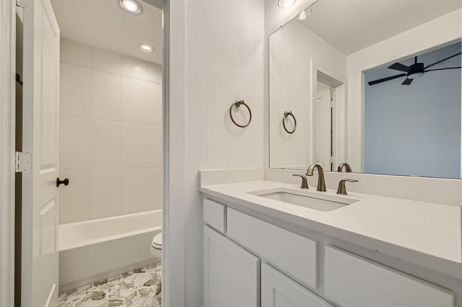 Full bathroom featuring tiled shower / bath, vanity, toilet, and ceiling fan