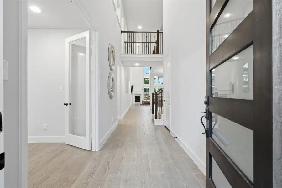 Bright and welcoming entryway with high ceilings, modern wood flooring, and a view into the living area. Features include a stylish glass front door, a staircase with a wooden railing, and an open, airy design. Bright and welcoming entryway with high ceilings, modern wood flooring, and a view into the living area. Features include a stylish glass front door, a staircase with a wooden railing, and an open, airy design.