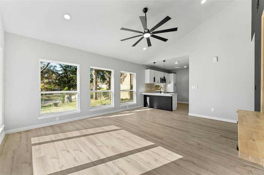 Unfurnished living room featuring ceiling fan, vaulted ceiling, light wood finished floors, and recessed lighting