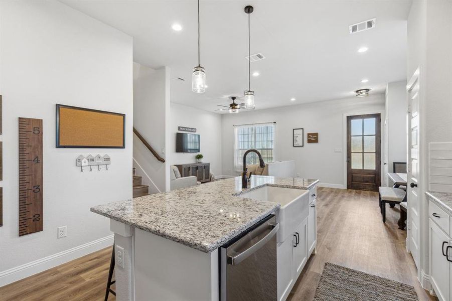 Kitchen with light hardwood / wood-style flooring, dishwasher, a kitchen island with sink, pendant lighting, and sink