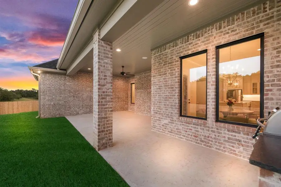 Patio terrace at dusk with ceiling fan, a patio area, a lawn, and area for grilling Patio terrace at dusk with ceiling fan, a patio area, a lawn, and area for grilling