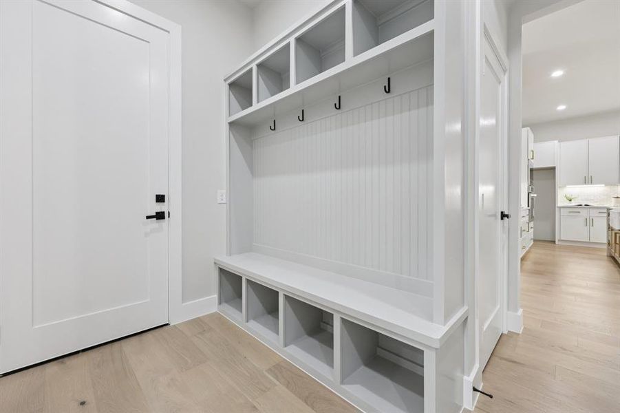 Built-in mudroom station featuring beadboard paneling, integrated bench seating, and upper storage cubbies