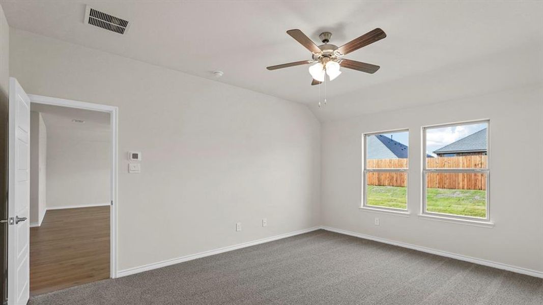 Spacious room featuring carpeting, two windows, a ceiling fan, and a light-colored wall finish