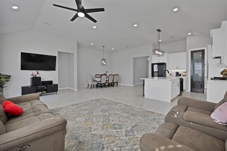 Living room featuring lofted ceiling, marble look floor tile, and recessed lighting