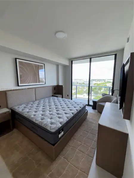 Floor-to-ceiling glass sliding doors, built-in wooden headboard with integrated side tables, and balcony with metal railing Floor-to-ceiling glass sliding doors, built-in wooden headboard with integrated side tables, and balcony with metal railing