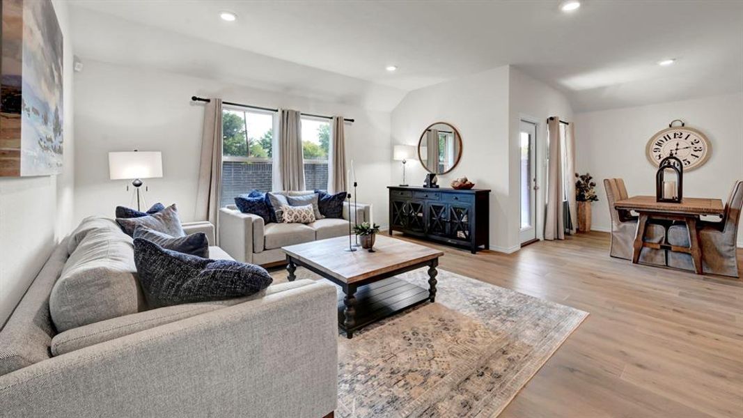 Living room featuring light wood-style flooring, recessed lighting, and vaulted ceiling