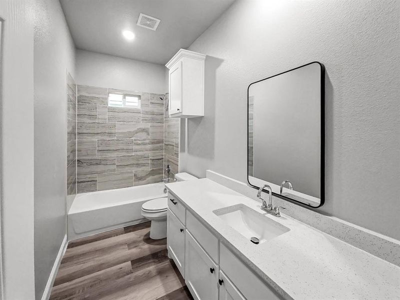 Bathroom featuring toilet, wood finished floors, vanity, and tub / shower combination Bathroom featuring toilet, wood finished floors, vanity, and tub / shower combination
