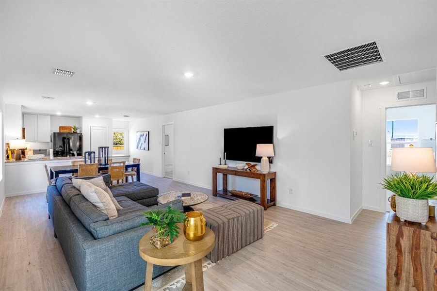 Living room with light wood-style flooring, recessed lighting, and plenty of natural light