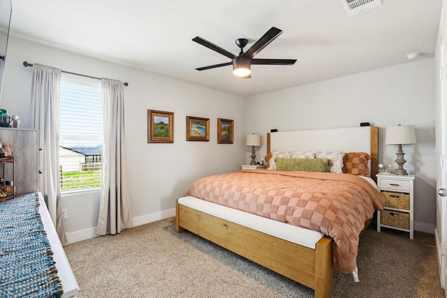 Carpeted bedroom with a ceiling fan, a window with horizontal blinds, and baseboard trim