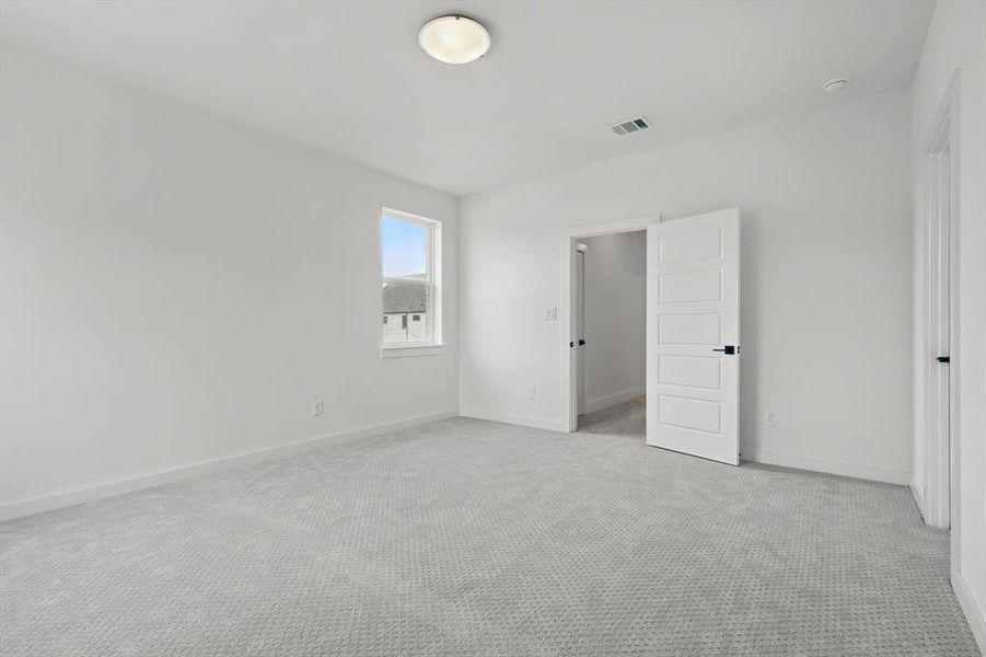 Unfurnished bedroom with light carpet and baseboards