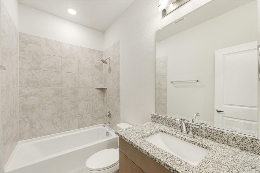 Bathroom with granite vanity, tiled shower-tub combo, and large mirror