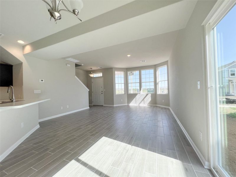 Unfurnished living room with baseboards, wood finish floors, recessed lighting, a sink, and a notable chandelier Unfurnished living room with baseboards, wood finish floors, recessed lighting, a sink, and a notable chandelier