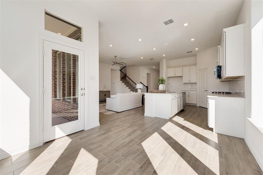 Kitchen featuring sink, an island with sink, white cabinets, light hardwood / wood-style flooring, and ceiling fan