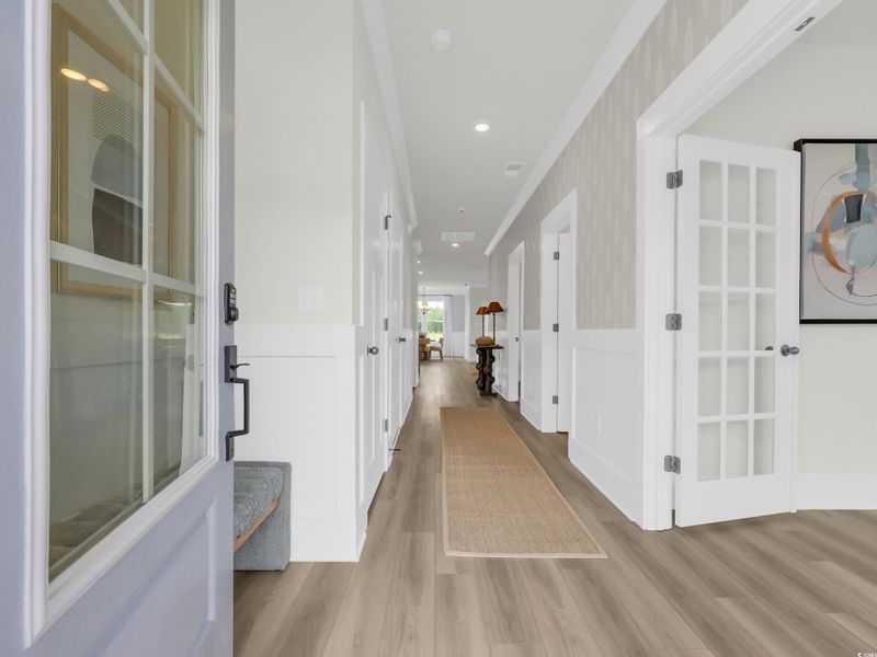 Hall with light wood-type flooring, recessed lighting, wainscoting, a decorative wall, and ornamental molding