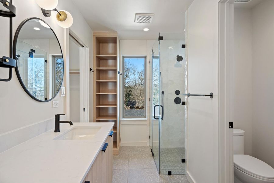 Full bathroom featuring toilet, a stall shower, baseboards, and visible vents