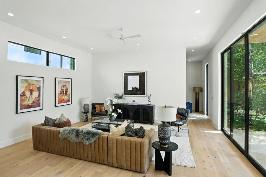 Living area featuring healthy amount of natural light, light wood finished floors, recessed lighting, and a ceiling fan Living area featuring healthy amount of natural light, light wood finished floors, recessed lighting, and a ceiling fan