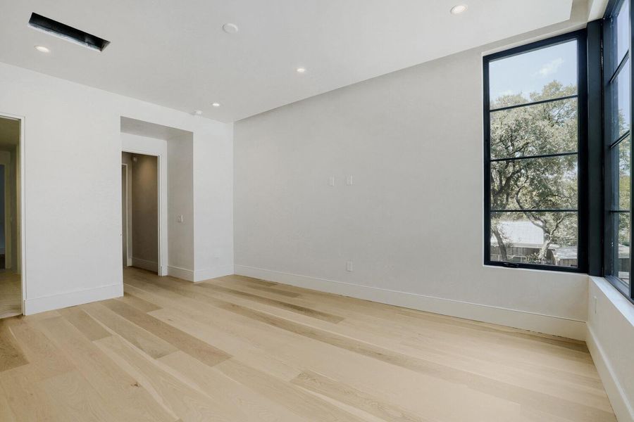 Ample natural light illuminates this spacious interior, showcasing light wood flooring and modern recessed lighting.