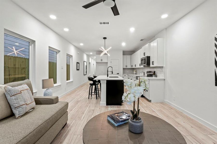 Living room with light wood finished floors, a ceiling fan, recessed lighting, and baseboards Living room with light wood finished floors, a ceiling fan, recessed lighting, and baseboards