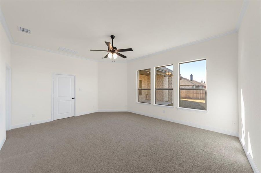 Unfurnished room featuring crown molding, carpet flooring, and ceiling fan Unfurnished room featuring crown molding, carpet flooring, and ceiling fan