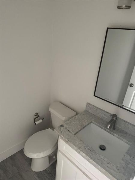 Bathroom with wood-type flooring, toilet, and vanity