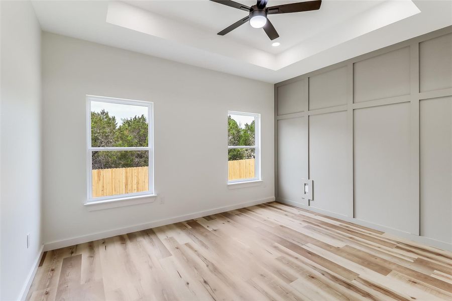 Unfurnished bedroom featuring a ceiling fan, light wood-style floors, a raised ceiling, baseboards, and recessed lighting