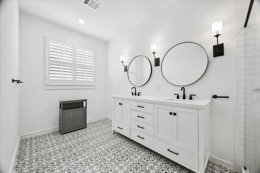 The expansive dual-sink vanity provides generous storage and countertop space while maintaining a sleek, modern aesthetic.