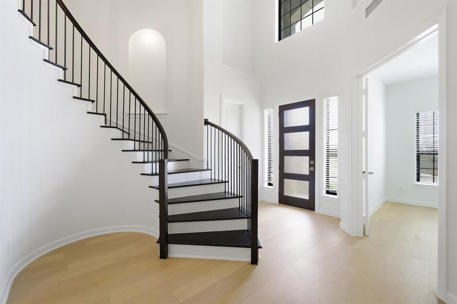 Grand entry featuring a curved staircase with dark risers and metal balusters Grand entry featuring a curved staircase with dark risers and metal balusters