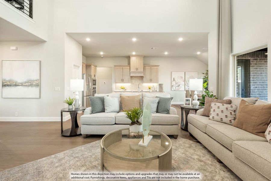 Open-concept living room with high ceilings, hardwood floors, and kitchen visible in background