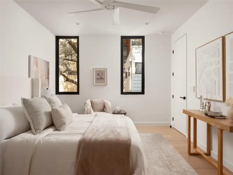 Hardwood floors and tall, slender windows define this serene, well-lit primary bedroom. Hardwood floors and tall, slender windows define this serene, well-lit primary bedroom.