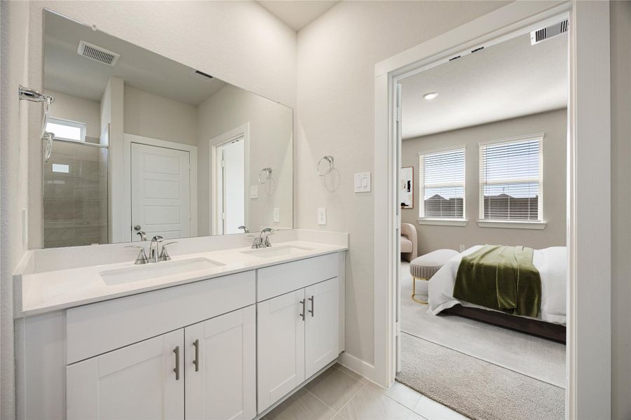 The primary bath offers a clean, modern design featuring a dual-sink vanity, sleek fixtures, and neutral finishes. A large mirror and walk-in shower enhance the bright, open feel, creating a relaxing space to start and end your day.