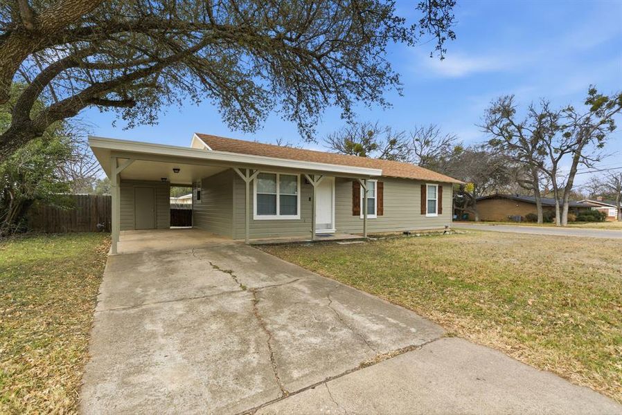Ranch-style home with concrete driveway, an attached carport, and a shingled roof Ranch-style home with concrete driveway, an attached carport, and a shingled roof