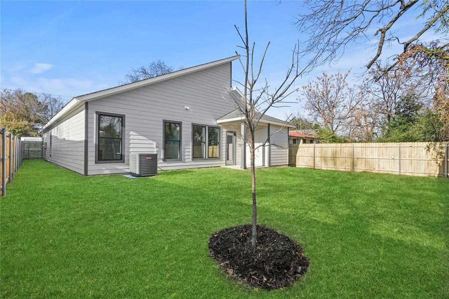 Rear view of property with central air condition unit and a lawn