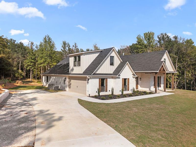 Modern inspired farmhouse featuring brick siding, driveway, a shingled roof, and a porch