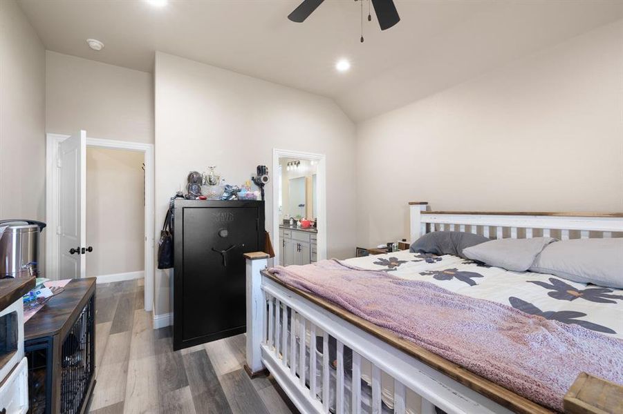 Bedroom with ceiling fan, vaulted ceiling, dark wood-type flooring, and ensuite bath