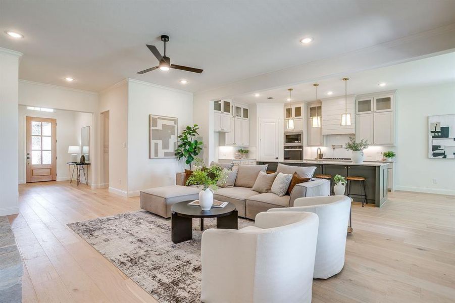 Living area with built in adjustable shelves, light engineered wood flooring, a stone fireplace with solid cedar mantle, ceiling fan, and french doors that open to a covered back patio. Living area with built in adjustable shelves, light engineered wood flooring, a stone fireplace with solid cedar mantle, ceiling fan, and french doors that open to a covered back patio.