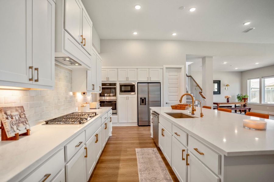 Show off your culinary skills in this fully loaded kitchen with quartz countertops, tile backsplash with under-cabinet lighting, crisp white cabinetry, a deep walk-in pantry and built-in stainless-steel appliances, including double electric ovens, a gas cooktop, dishwasher and microwave.