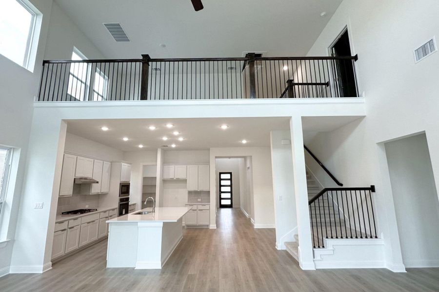 A striking open-concept layout showcasing a modern kitchen and soaring ceilings with an upper-level overlook.