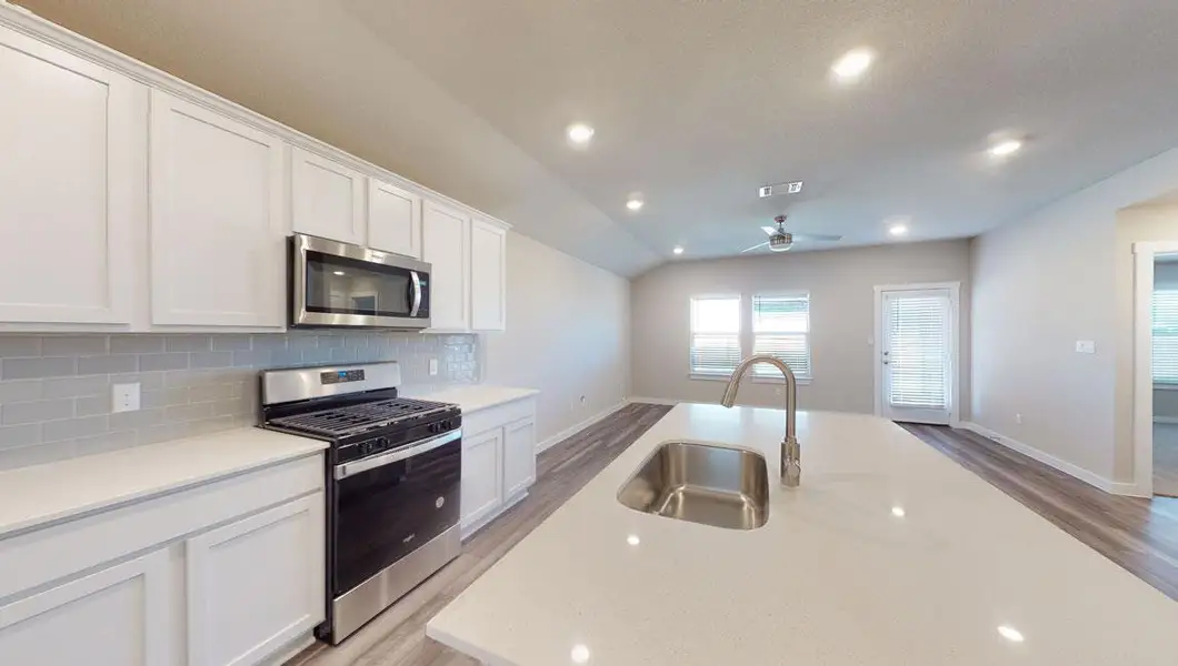 Kitchen with appliances with stainless steel finishes, white cabinetry, recessed lighting, decorative backsplash, and light stone counters