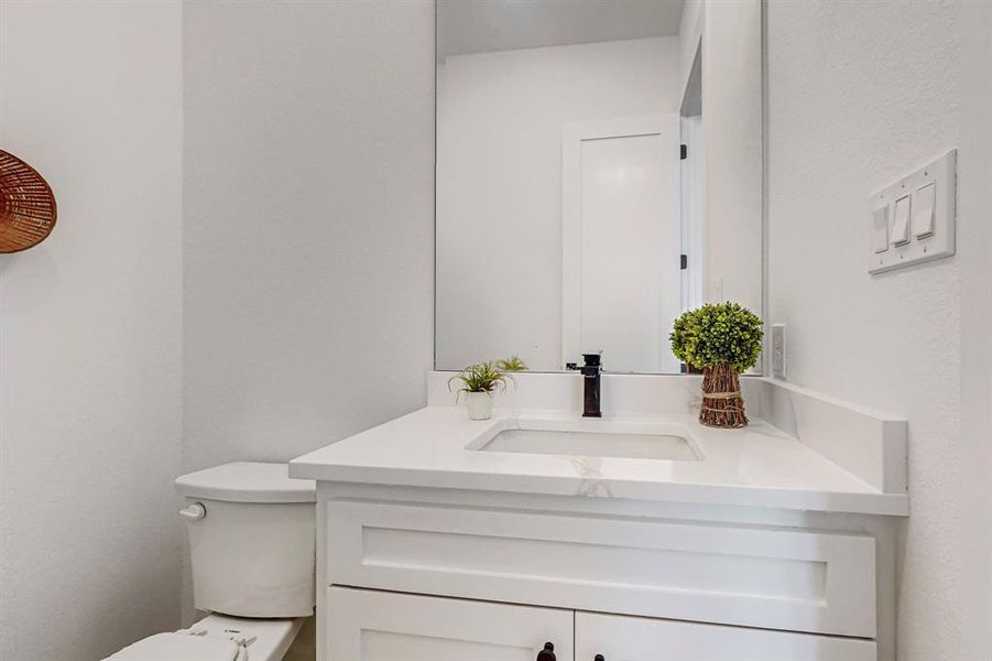 Hall Half Bathroom featuring vanity with extensive cabinet space and toilet