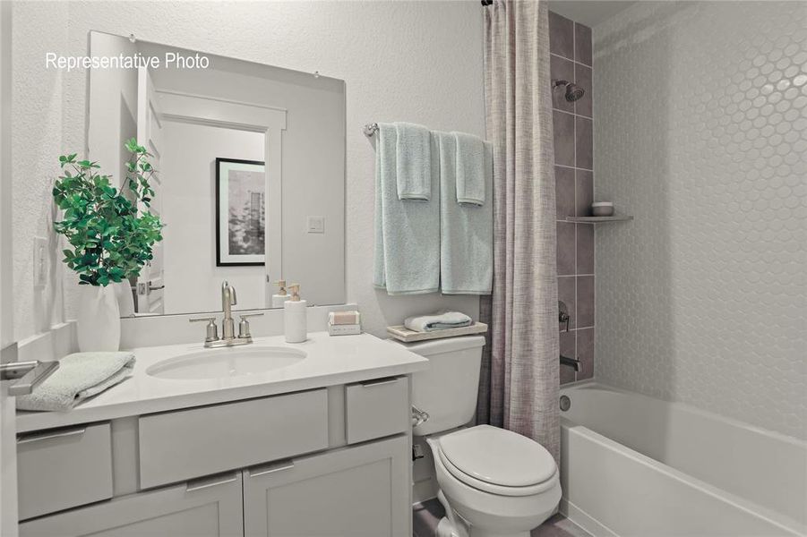 White vanity with an integrated sink and brushed nickel faucet, large frameless mirror, and a full bathtub with a shower featuring honeycomb tile surround White vanity with an integrated sink and brushed nickel faucet, large frameless mirror, and a full bathtub with a shower featuring honeycomb tile surround