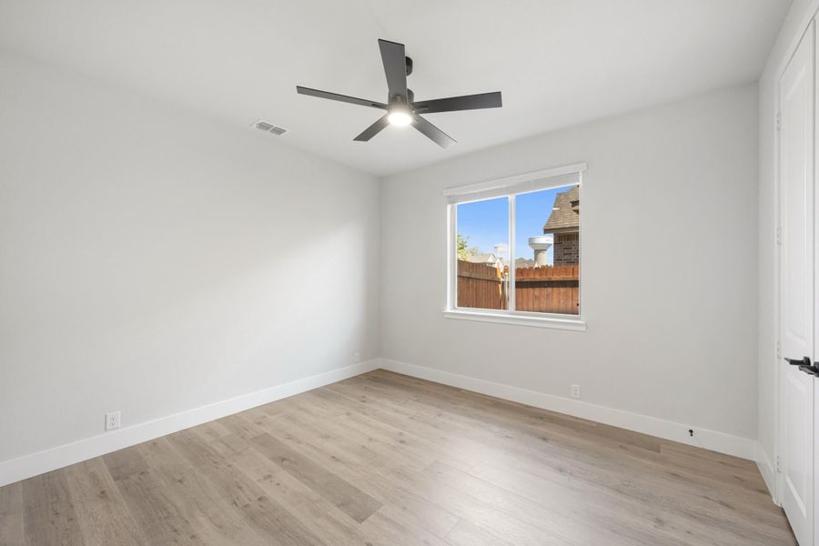Empty bedroom with light wood floors, white walls, ceiling fan, and single window Empty bedroom with light wood floors, white walls, ceiling fan, and single window
