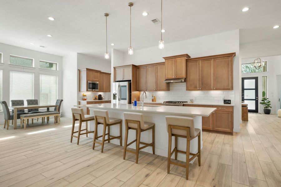 The kitchen boasts a large island with a sleek faucet and large single basin sink. Upgraded with built-in stainless steel appliances, a 5 burner gas range, and sleek wood cabinets, this kitchen is ideal for cooking for the whole family or hosting holidays! The kitchen boasts a large island with a sleek faucet and large single basin sink. Upgraded with built-in stainless steel appliances, a 5 burner gas range, and sleek wood cabinets, this kitchen is ideal for cooking for the whole family or hosting holidays!