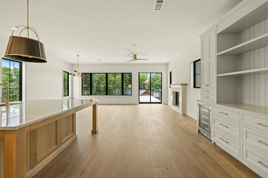 Unfurnished living room featuring healthy amount of natural light, a fireplace, light wood finished floors, and ceiling fan