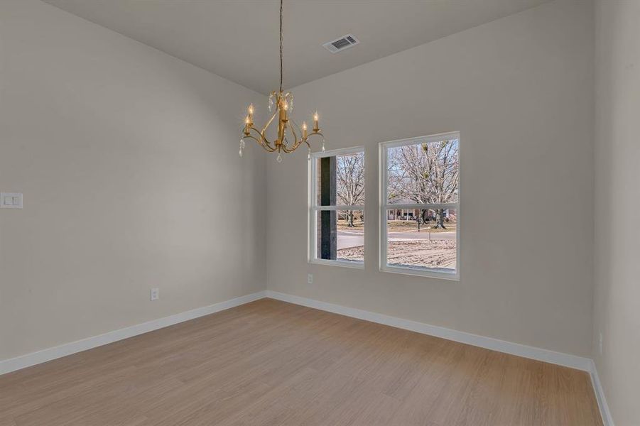 Empty room featuring light hardwood / wood-style flooring and a chandelier